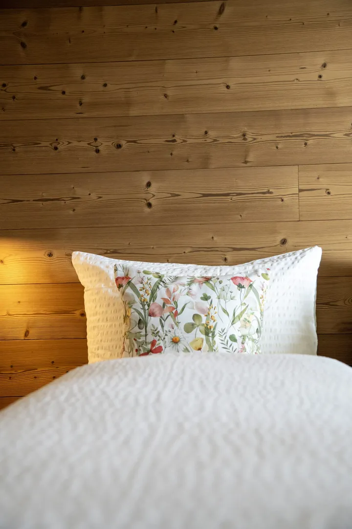 Frisch bezogenes Bett mit Blumenkissen