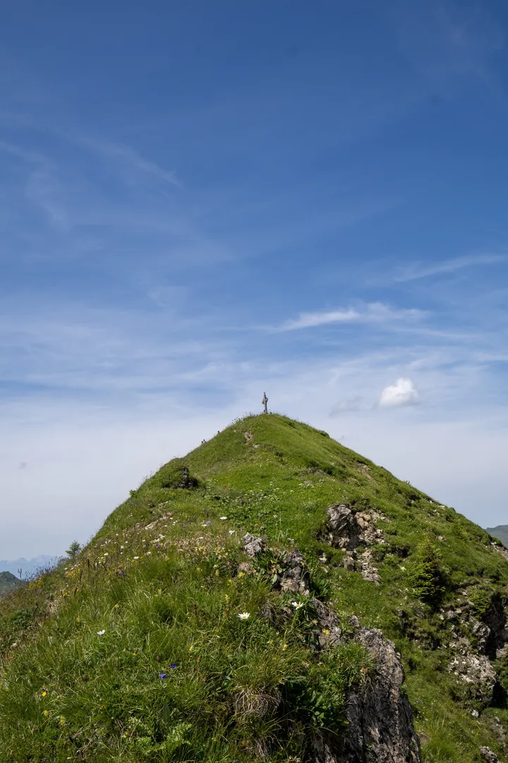 Grasbewachsener Gipfel unter blauem Himmel