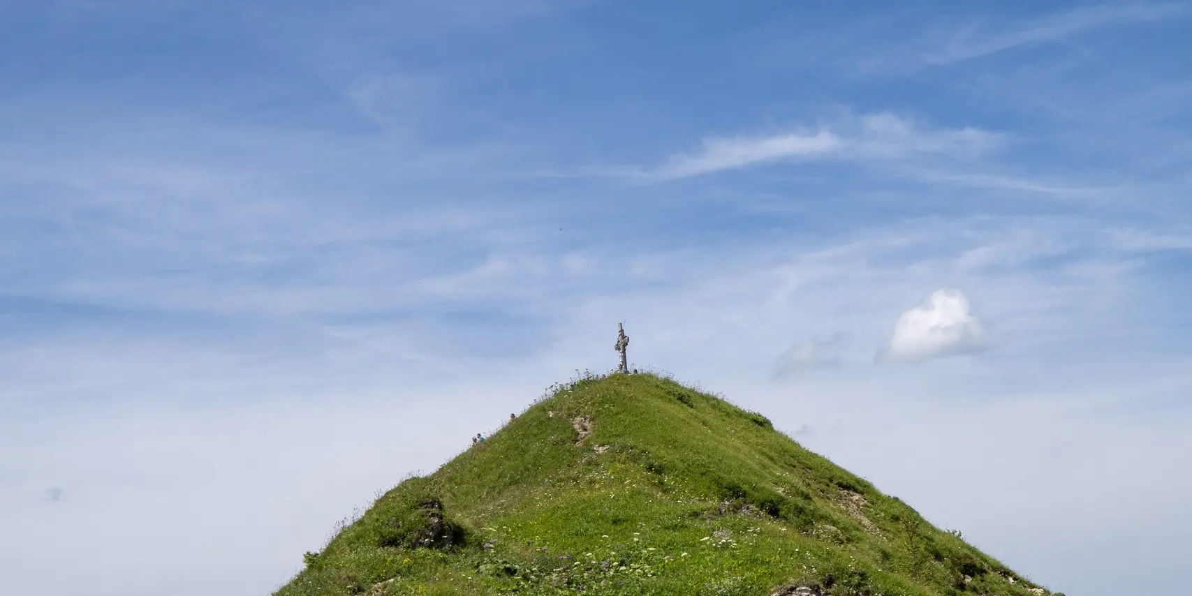 Grasbewachsener Gipfel unter blauem Himmel