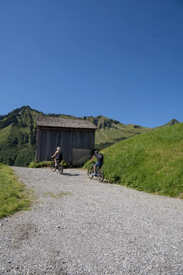 Radfahrer auf dem Schotterweg bei einer Alphütte