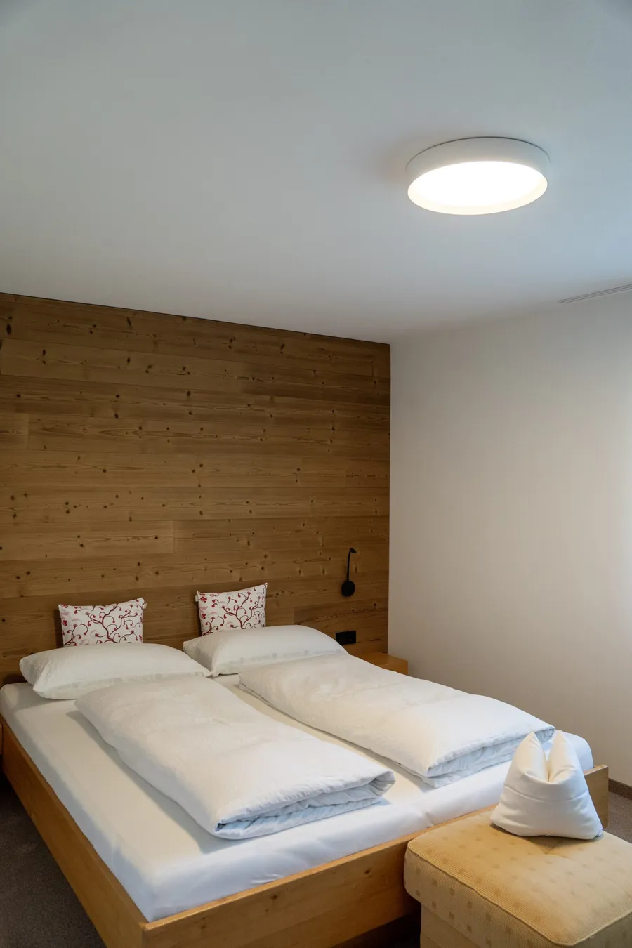 Schlafzimmer mit Doppelbett und Holzwand