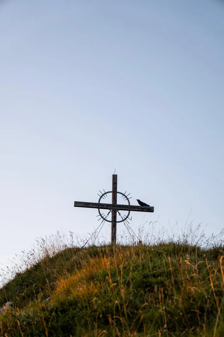 Gipfelkreuz auf einer Bergkuppe im Herbst